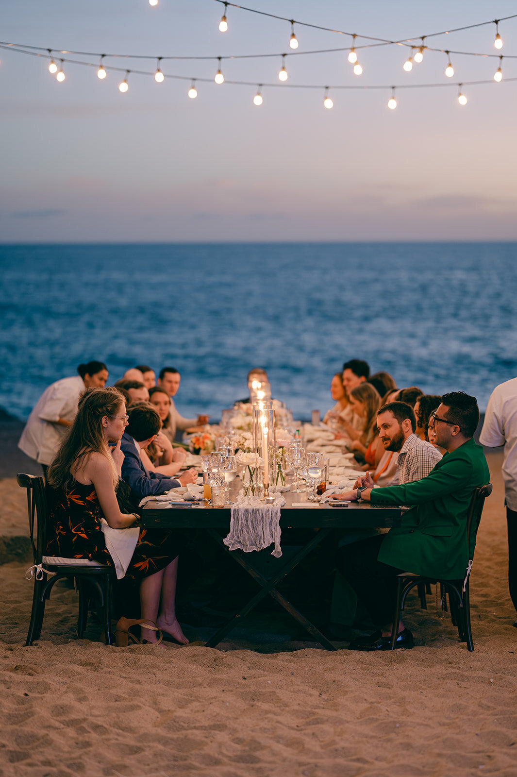 Candlelit beach wedding dinner during sunset in Cabo San Lucas, Mexico.