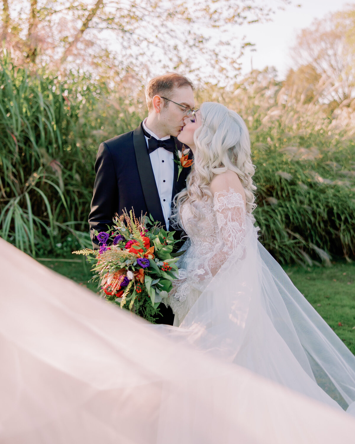 A wedding couple kissing as a veil flows in front of them 