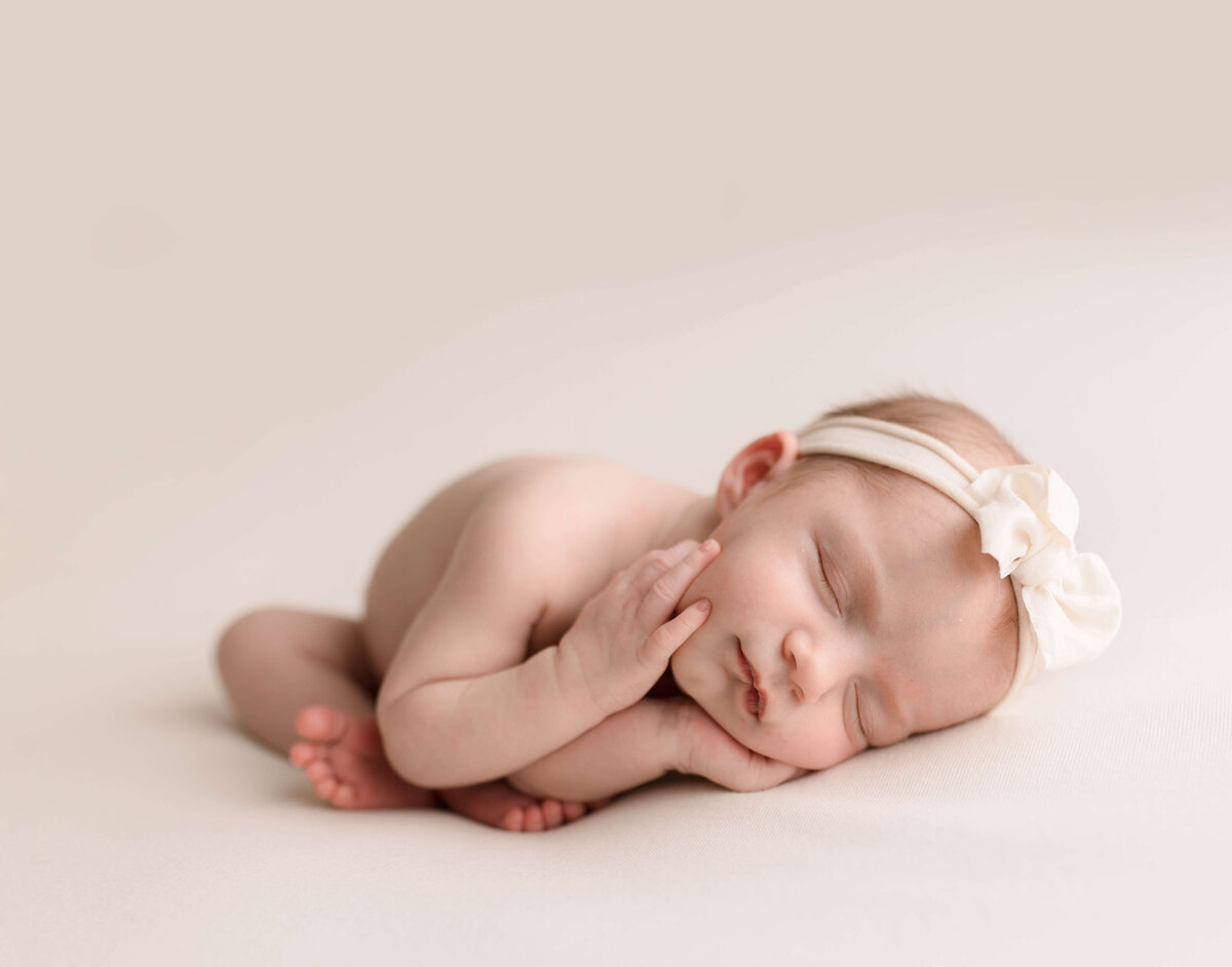 newborn lying down on cream fabric