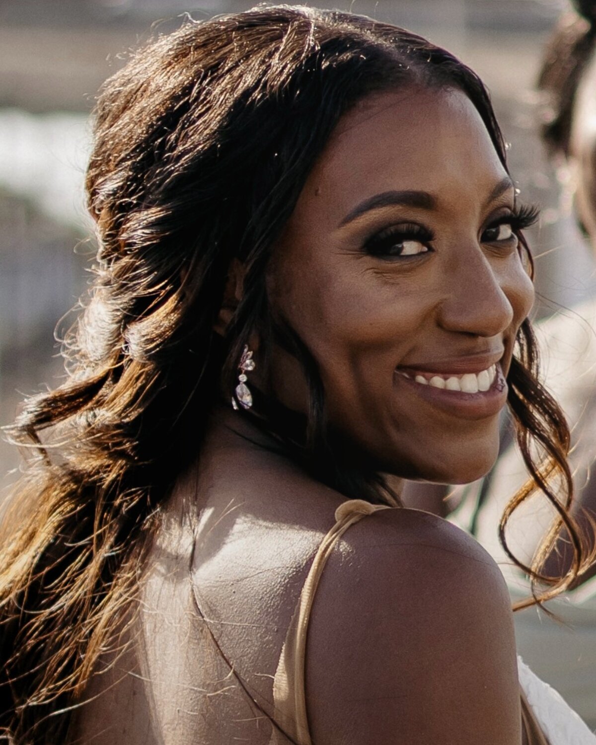 Bride with full glam wedding makeup and soft curls smiling confidently on her big day.