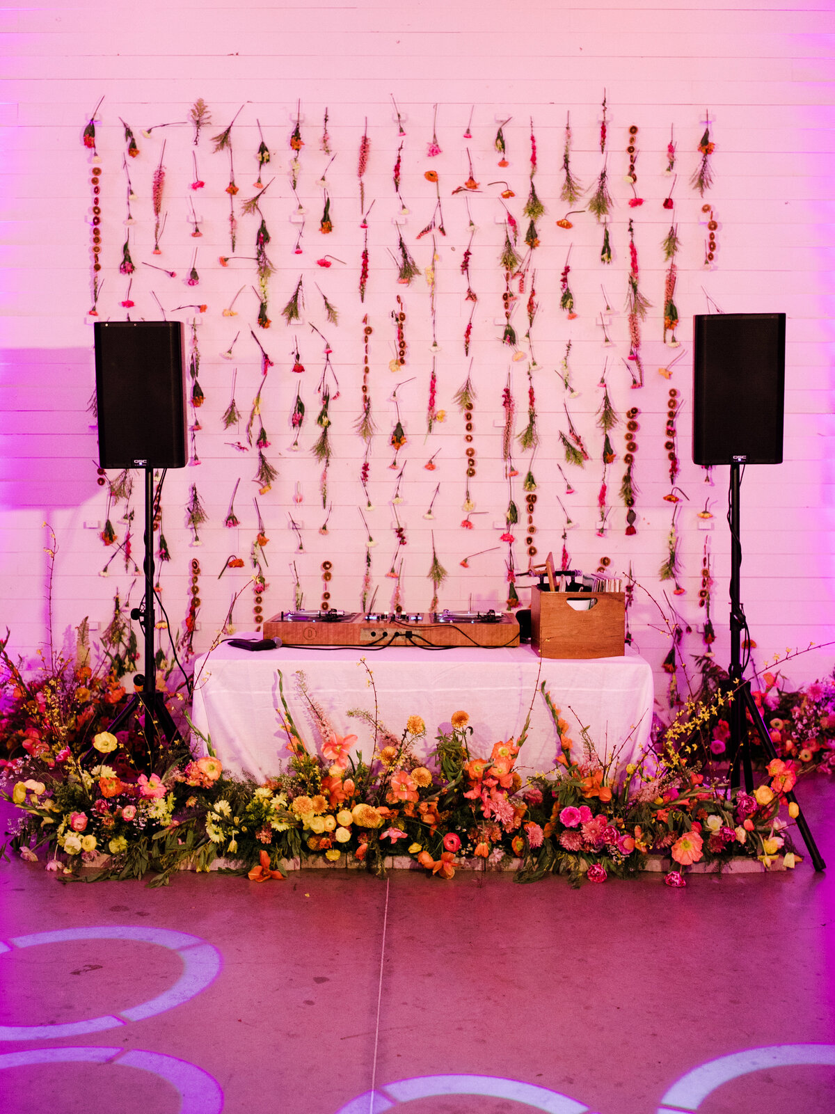 Table with colorful florals surrounding it with two speakers