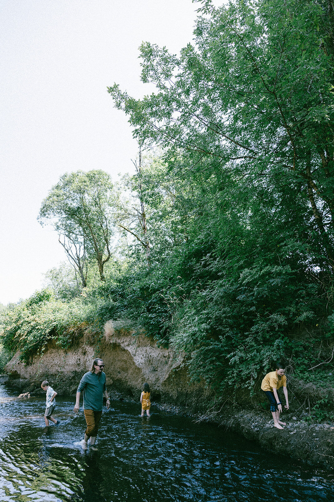 Family plays in river together while taking candid documentary style photos in Oregon. 