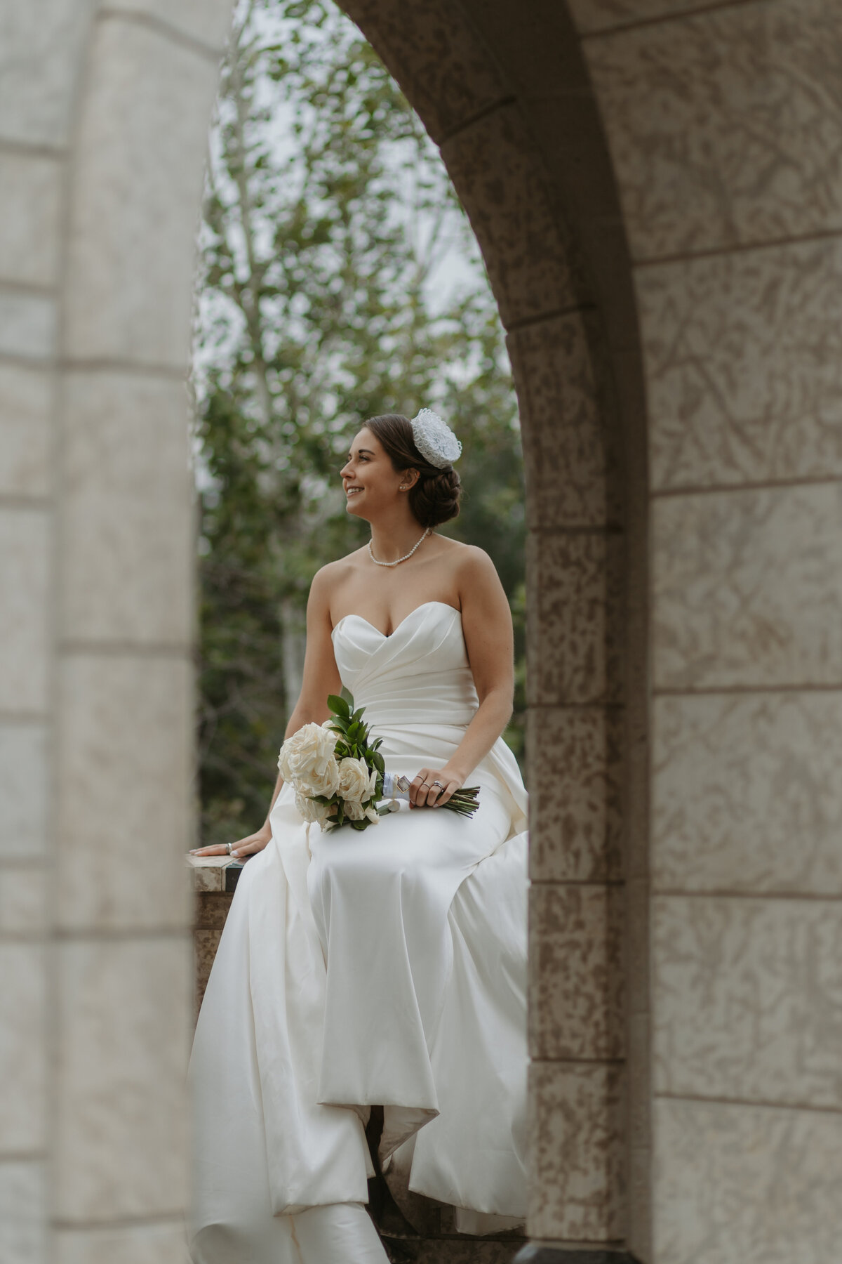 bride posed through arch of u of a botanical gardens