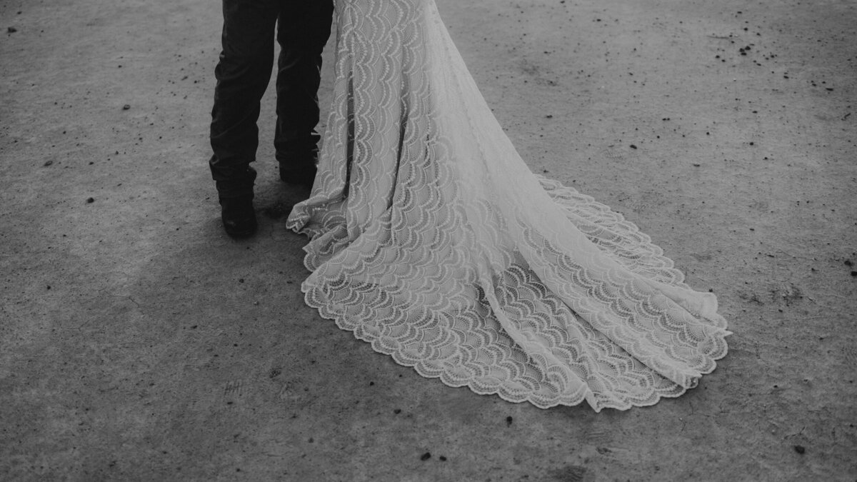 brides lace wedding dress train against the desert floor