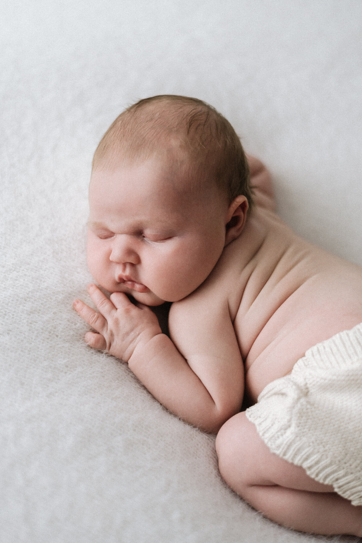 Baby girl laying on her tummy sleeping at a newborn photoshoot in billingshurst