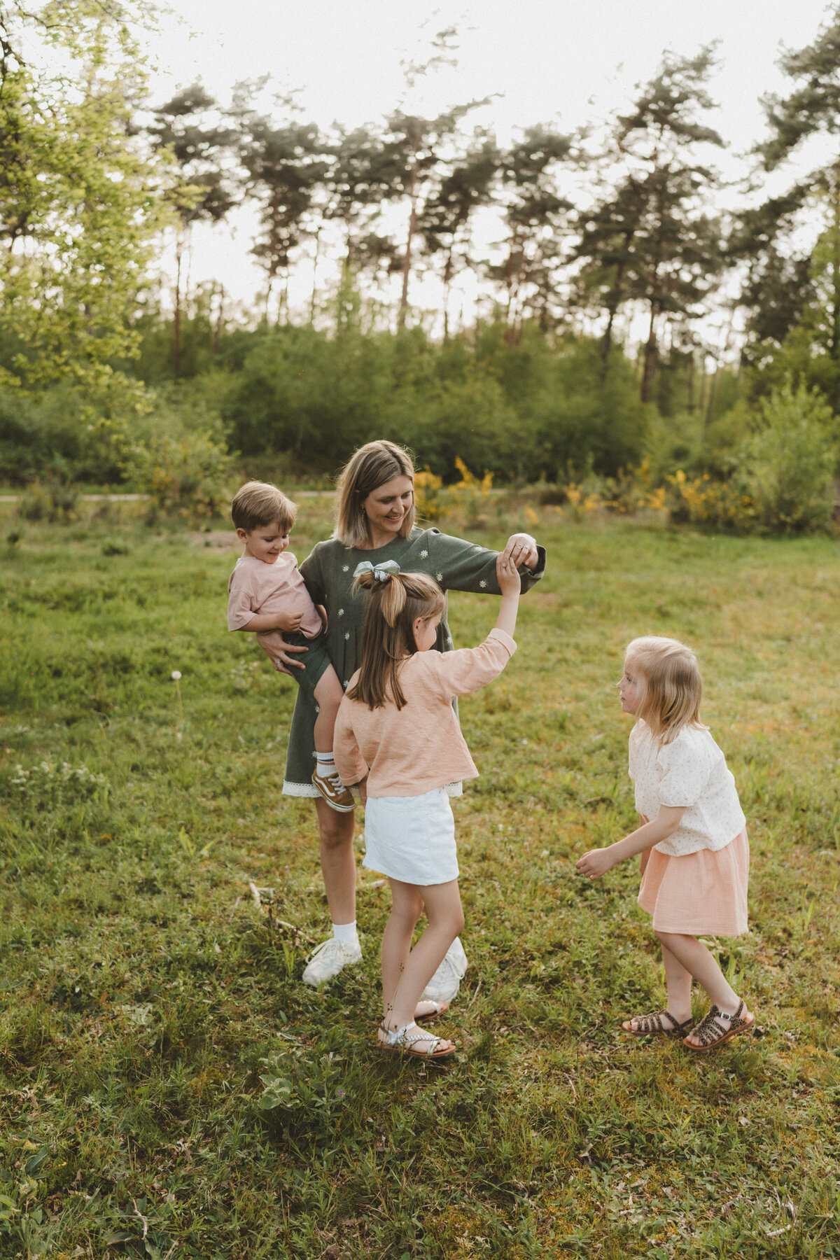 Moeder speelt met haar drie kinderen tijdens fotoshoot.