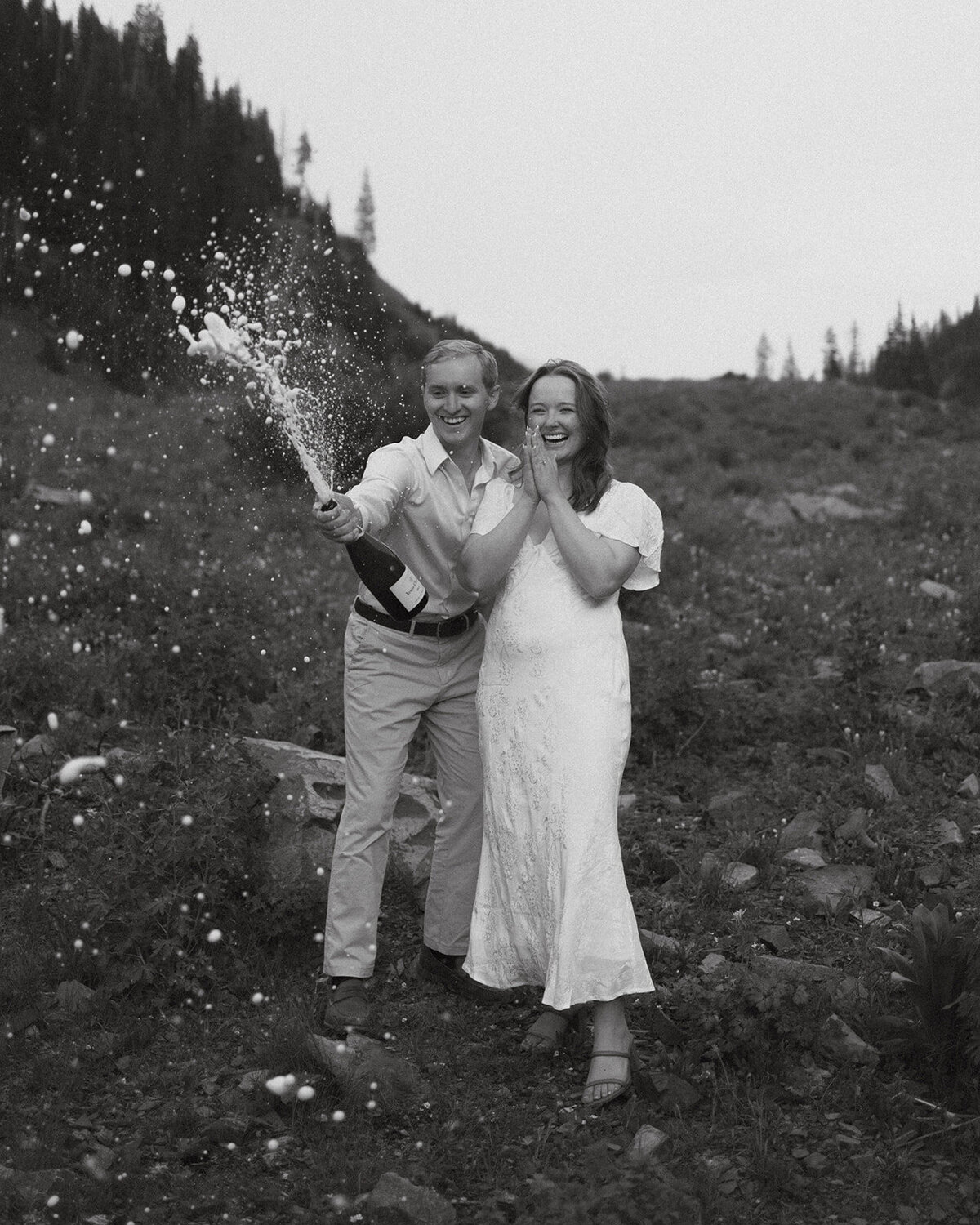 couple with open champagne bottle smiling and celebrating