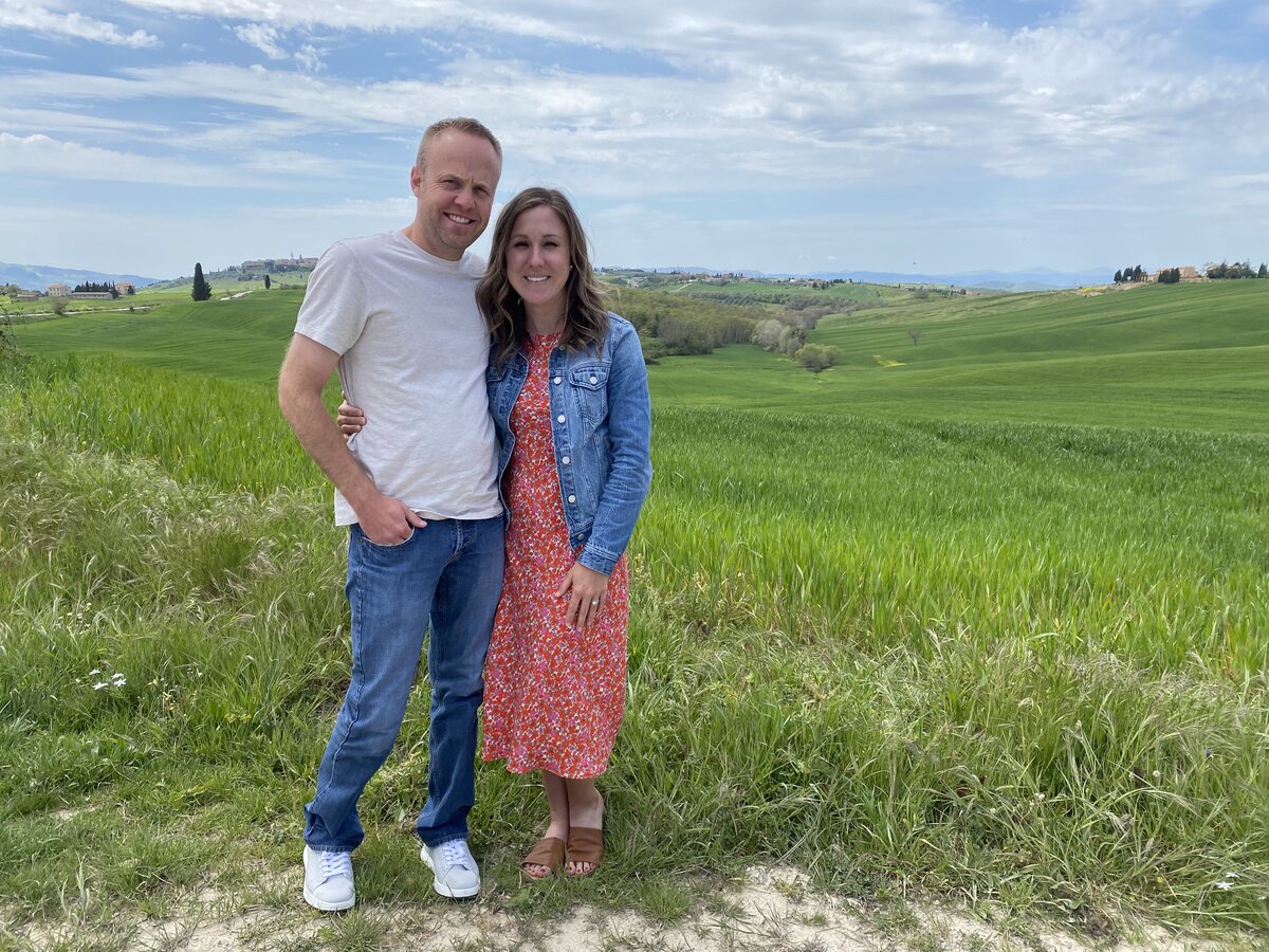 Couple posing in a beautiful field in Italy on their DWD planned vacation