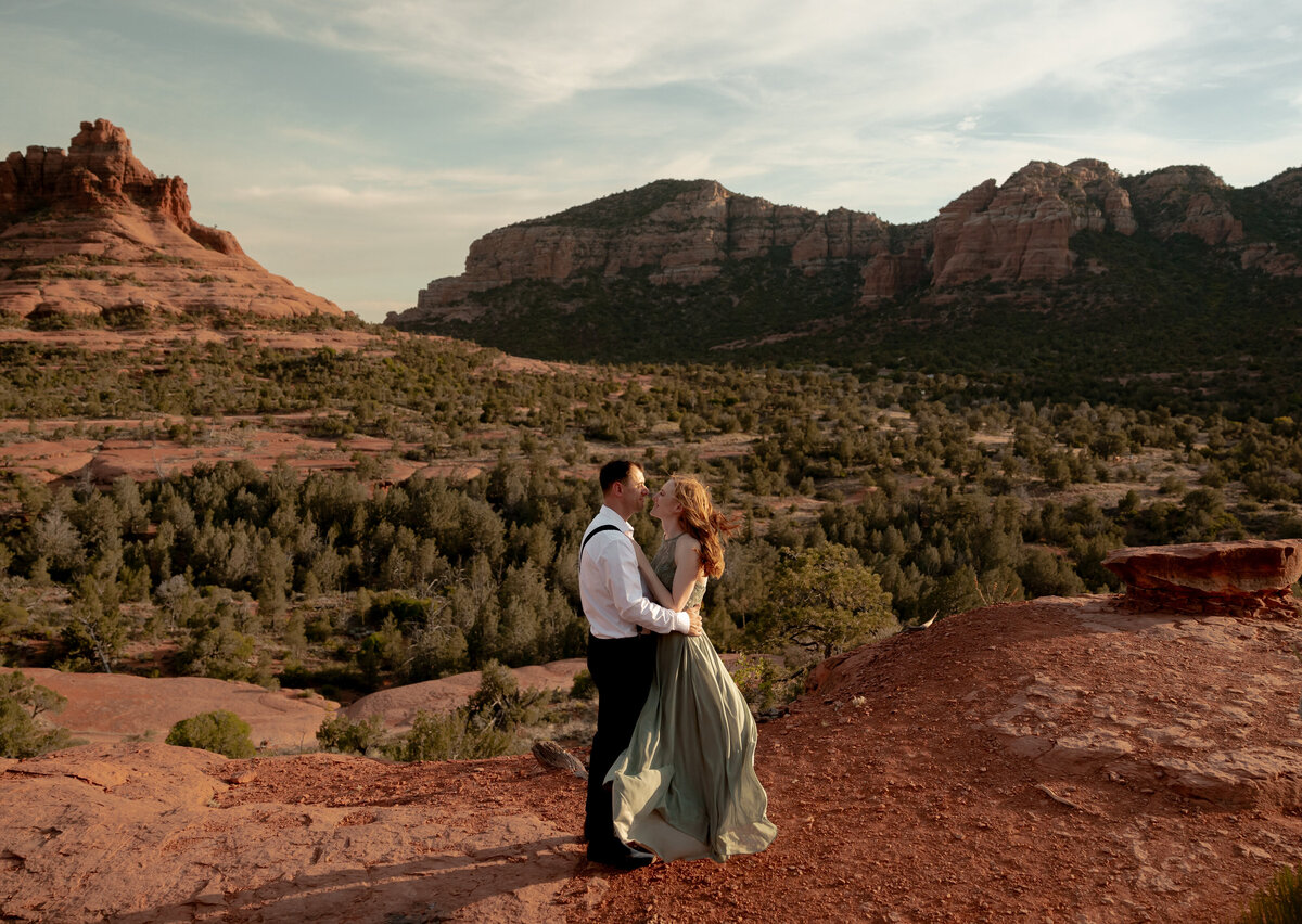 Couple standing against red rock backdrop during Sedona engagement session