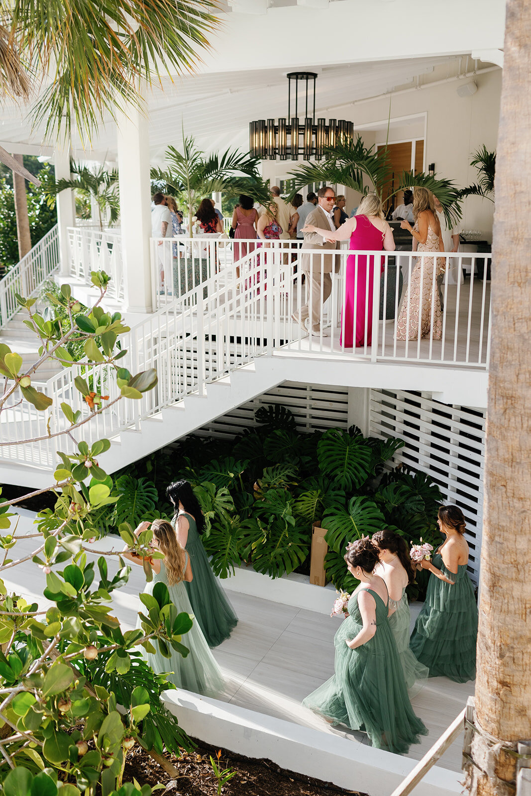 A cinematic view of bridesmaids in flowing dresses walking down the Cheeca Lodge staircase.
