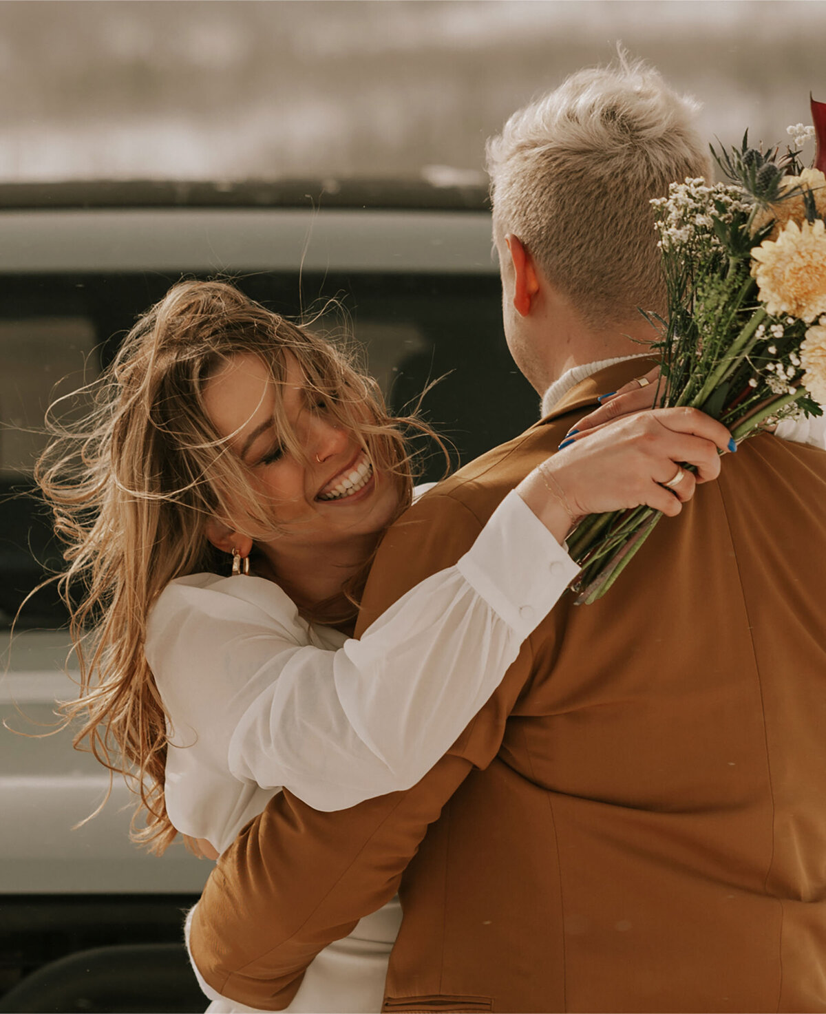 private elopement couple with flowers embrace in a hug on a snowy day in Bend, Oregon