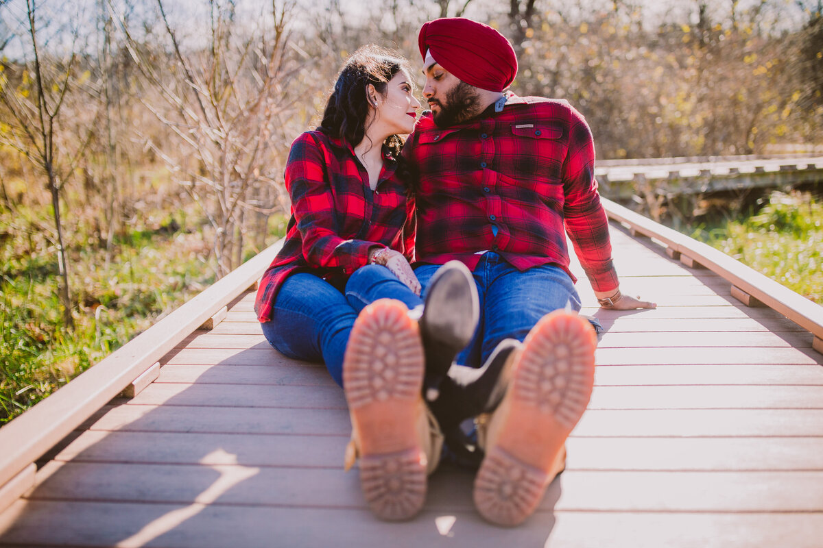 A couple sitting on a walkway in a kansas park wearing plaid and timberland boots