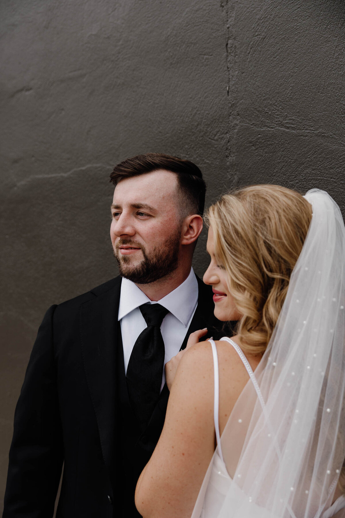 A newlywed standing together looking off to the side