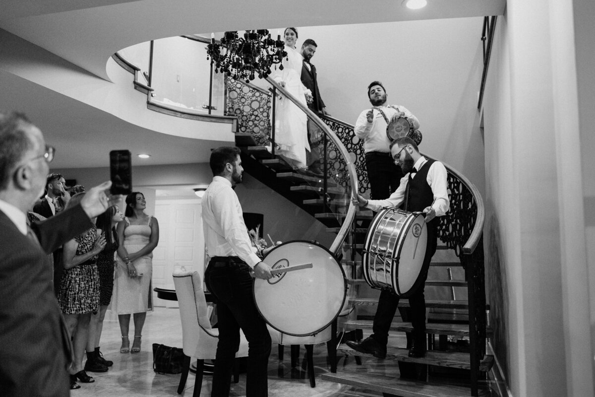 A live band going down the stairs while accompanying the bride and groom