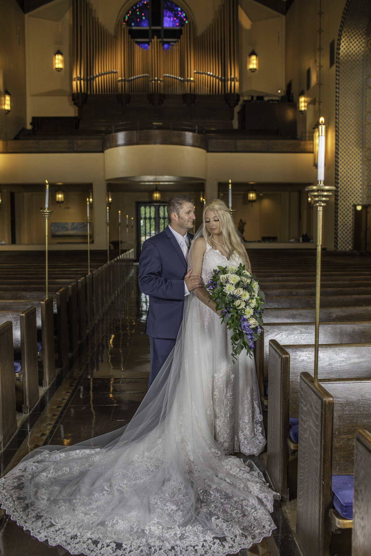 Bride and groom pose in the church aisle