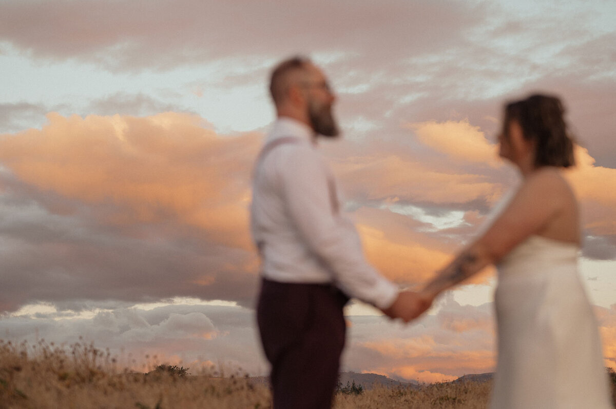 elopement couple holding hands and exchanging vows underneath pink clouds in Rowena Crest View in the Dalles Oregon