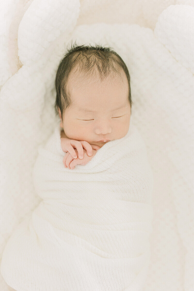 白いブランケットとベッドの中でスヤスヤ寝ている赤ちゃんが可愛らしい、ナチュラル・ニューボーンフォト