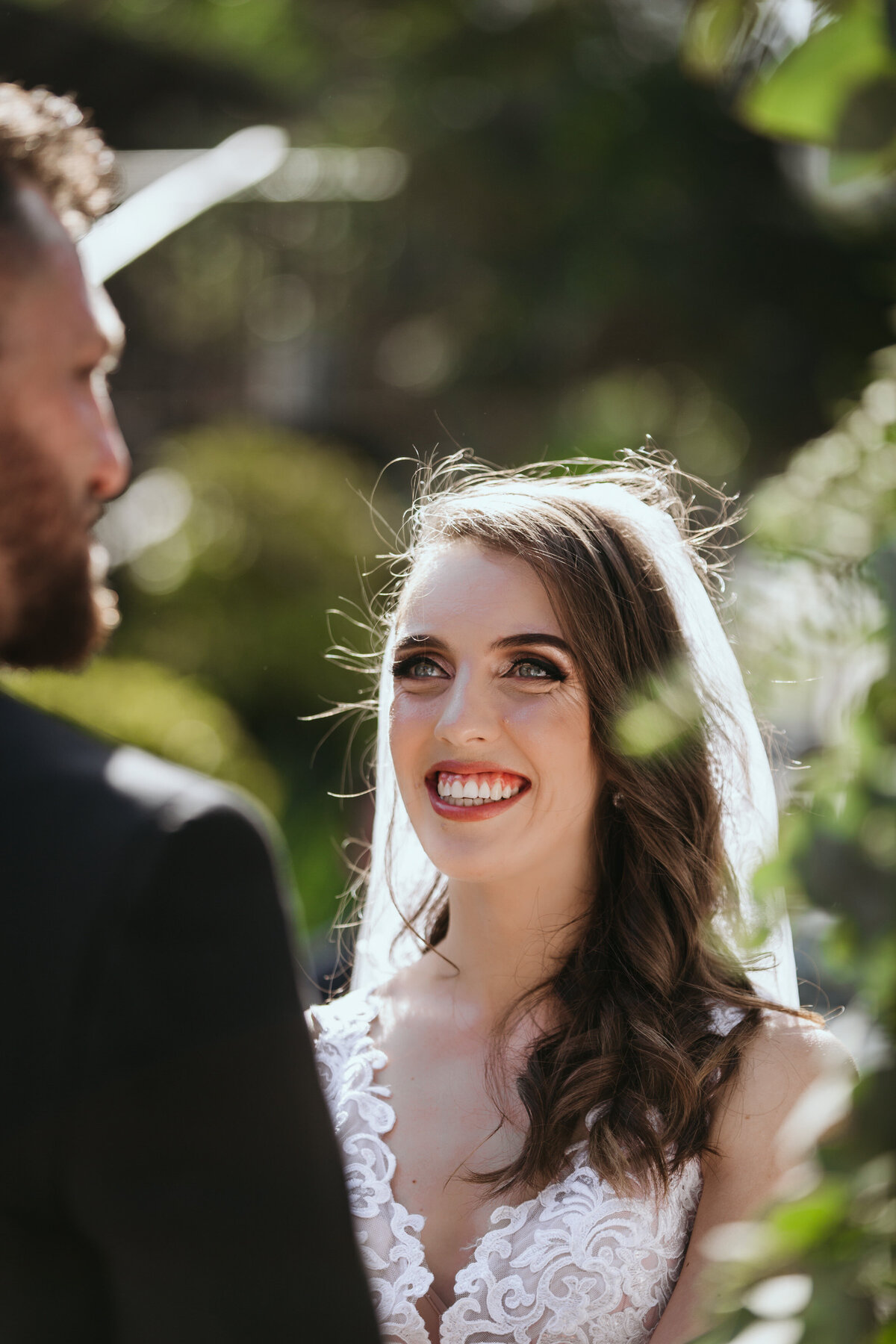 The bride smiles broadly as she looks into the groom's eyes while getting married. 