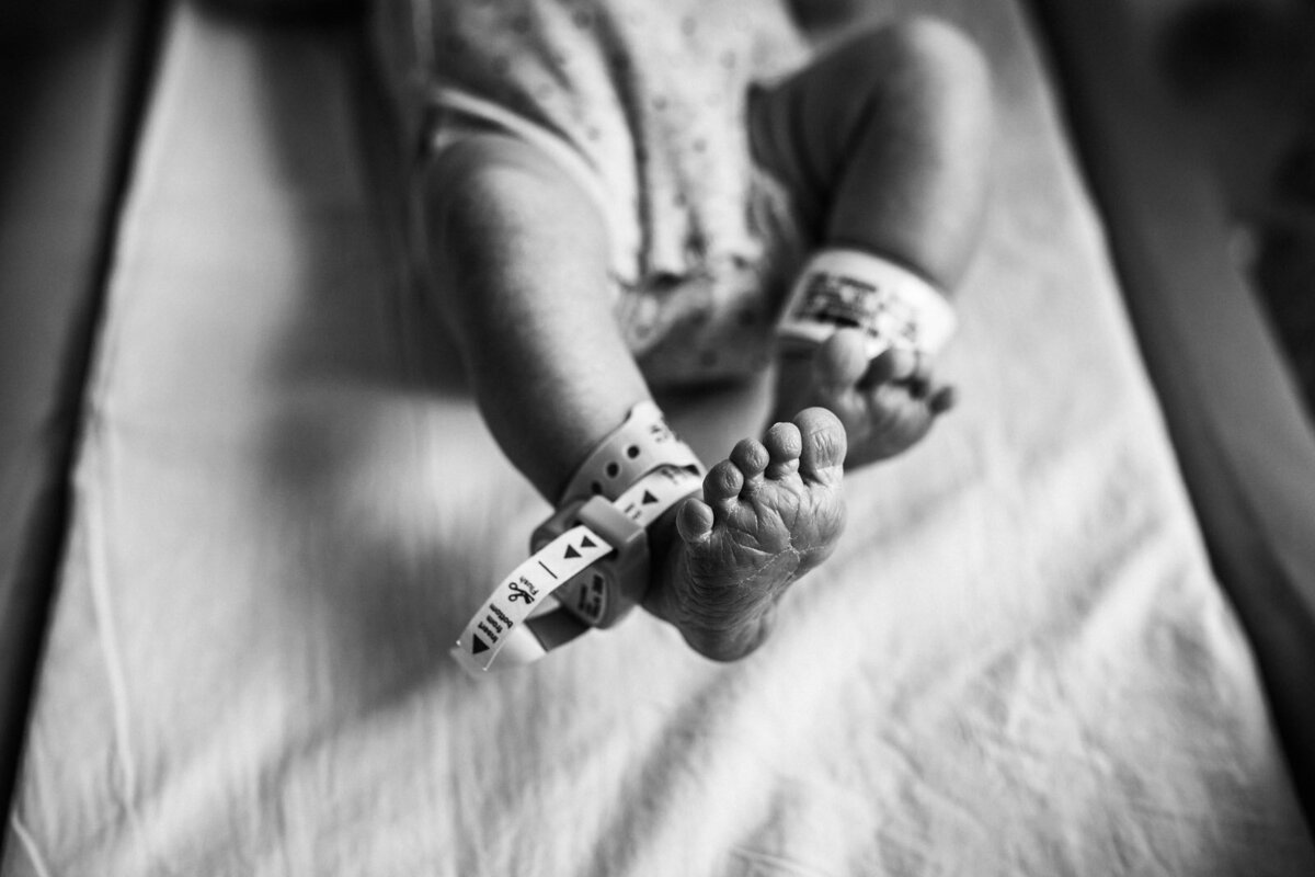 baby feet stretching while laying in bassinet with hospital bracelets on ankles