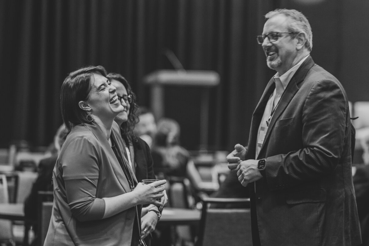 Three people laugh happily while in discussion.