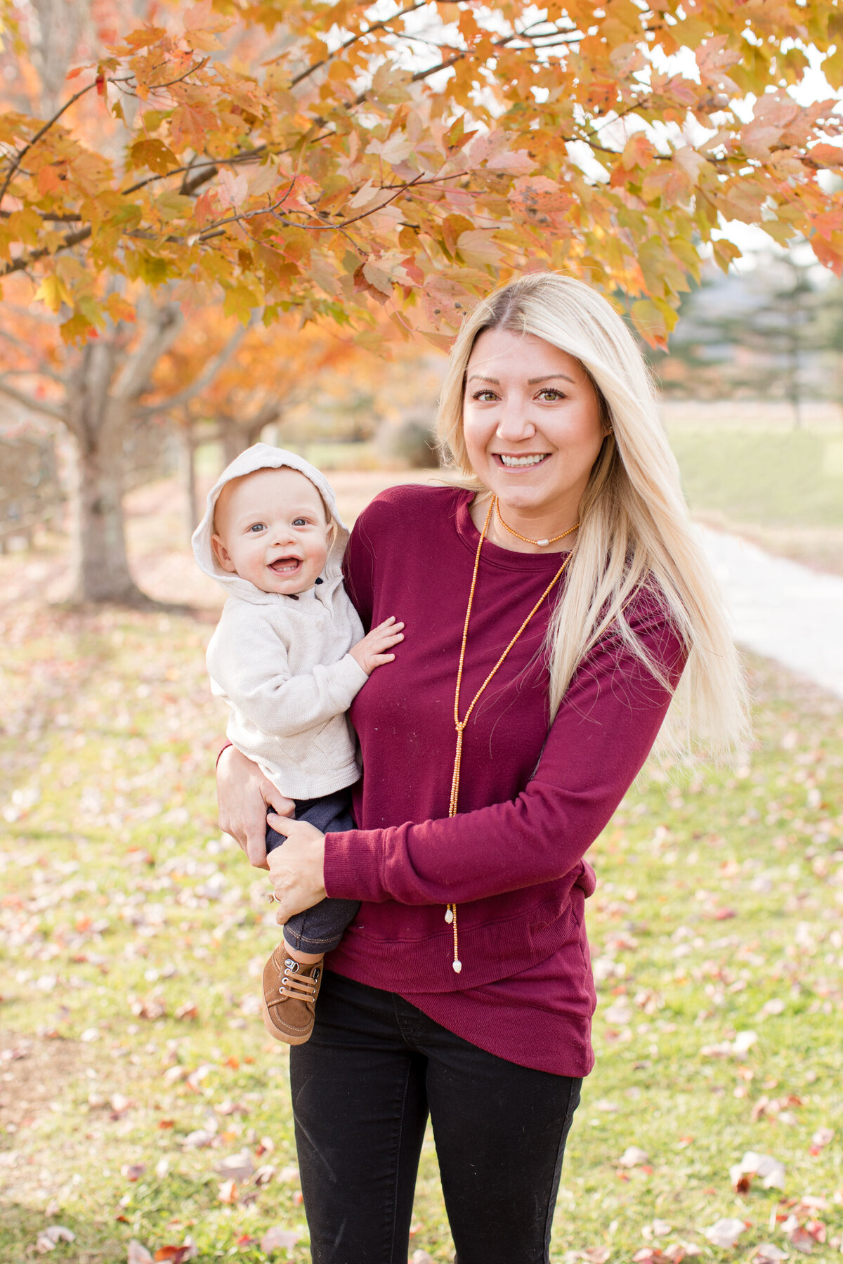 Family photo session in Boone, NC shows a woman holding her toddler and smiling at the camera.