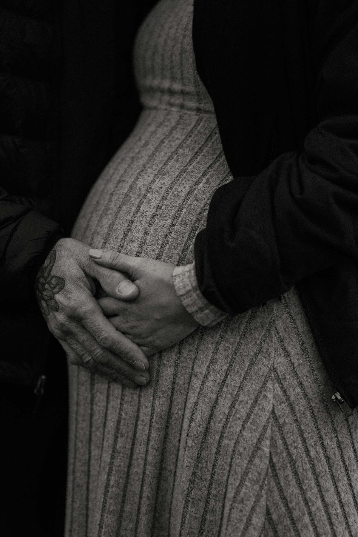 Close-up of a couple gently touching the mother's belly, capturing a tender moment of connection during their maternity session.