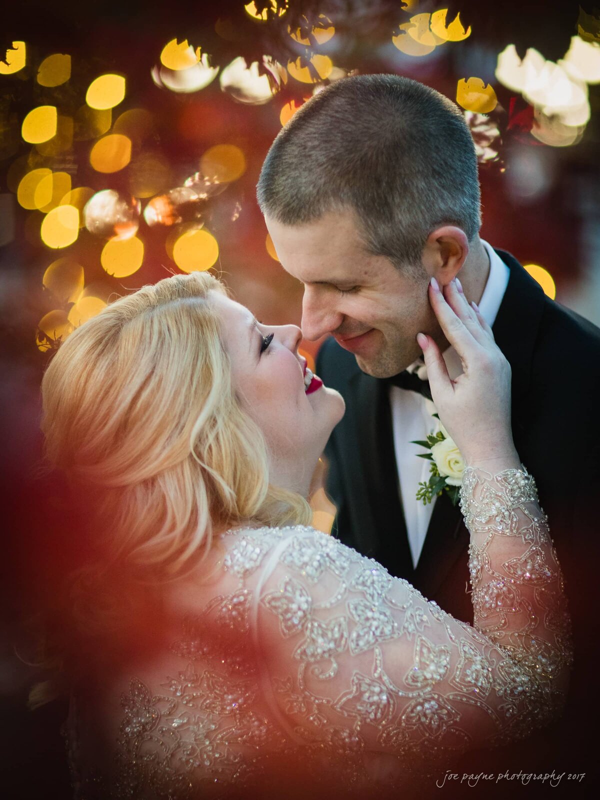 A bride touching a groom's face as they smile and are about to kiss.