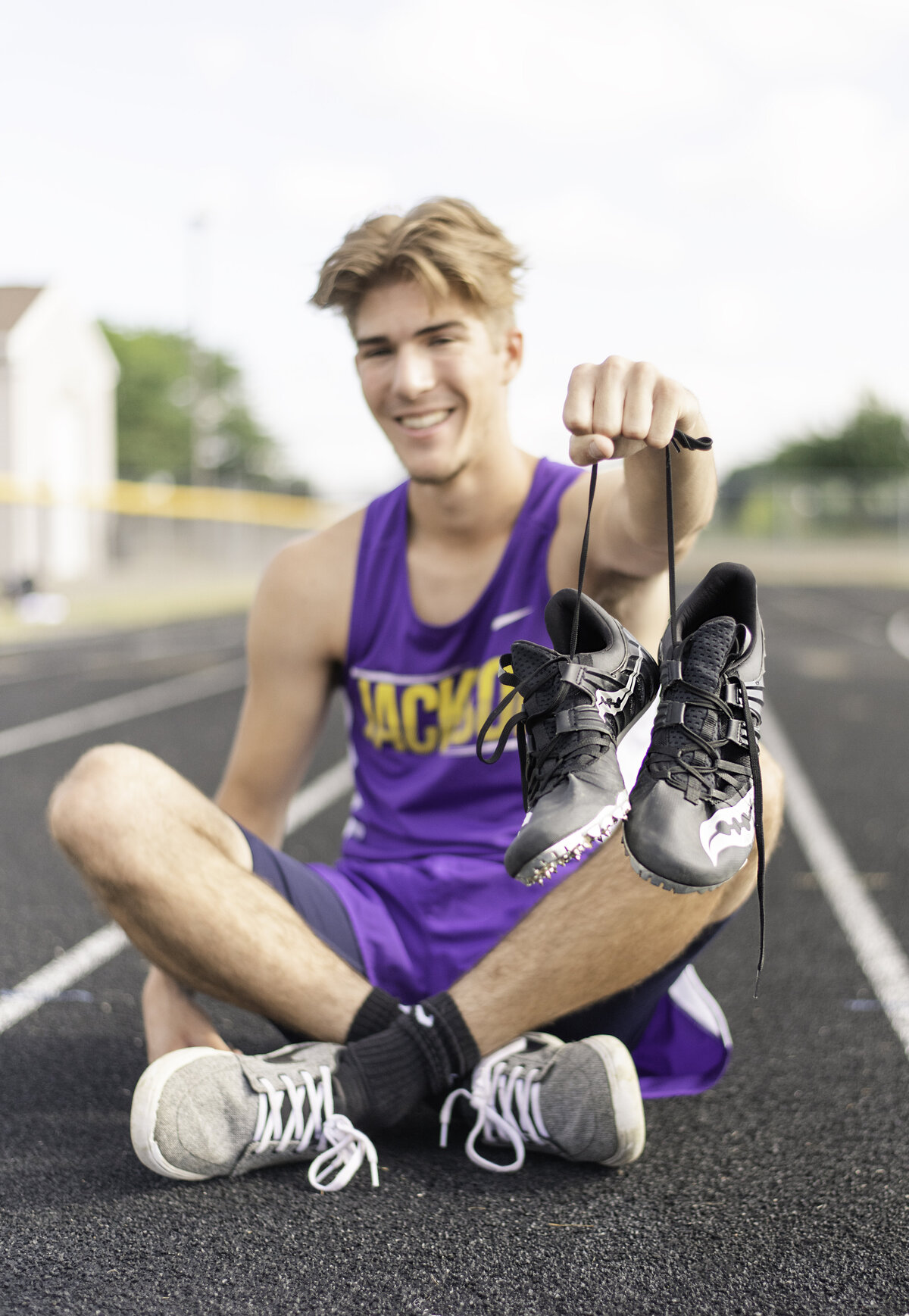 High School Senior Boy Track holding cleats