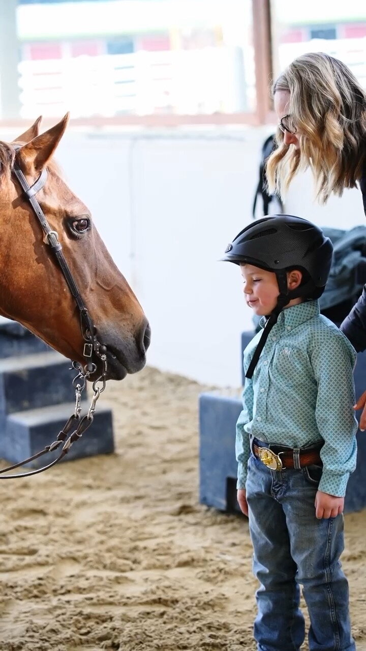 a young boy and a horse face each other, both are looking at each other sweetly