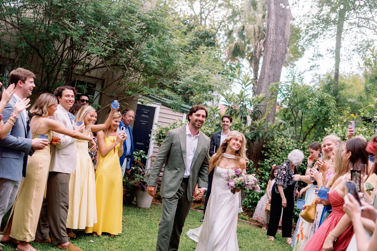 Bride and groom walking back up the aisle hand in hand during their backyard wedding in Charleston, South Carolina.
