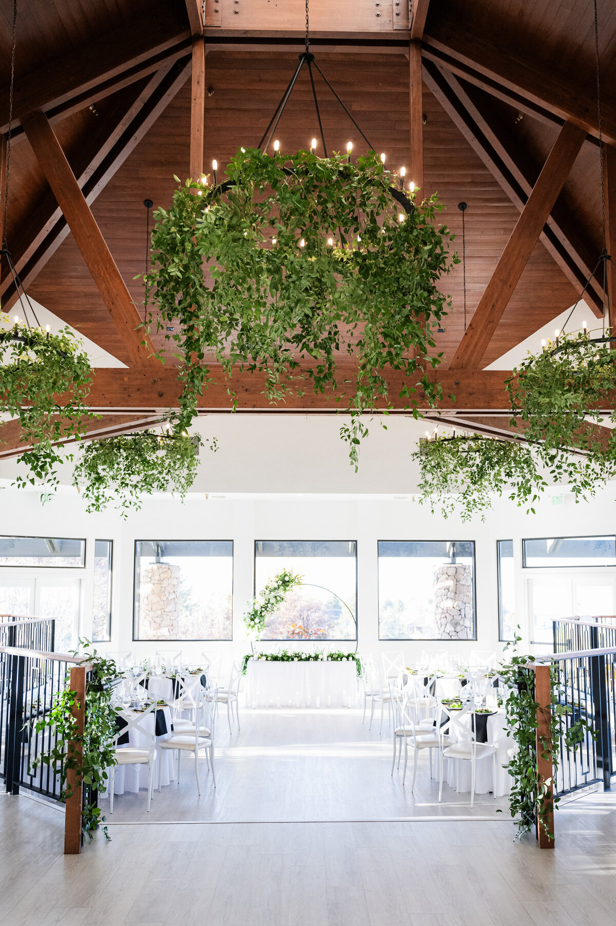 A bright, grand room at The Oaks at Plum Creek has greenery hanging from the chandeliers and is set for a wedding ceremony.