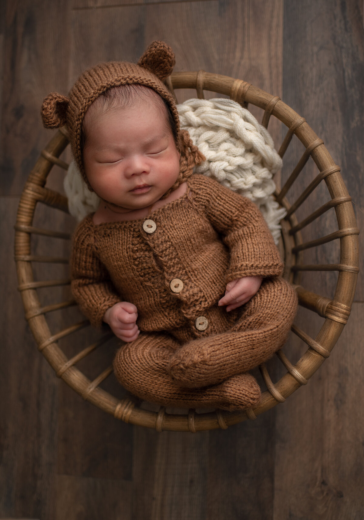 baby in bear bonnet sleeping in a bowl at newborn photoshoot