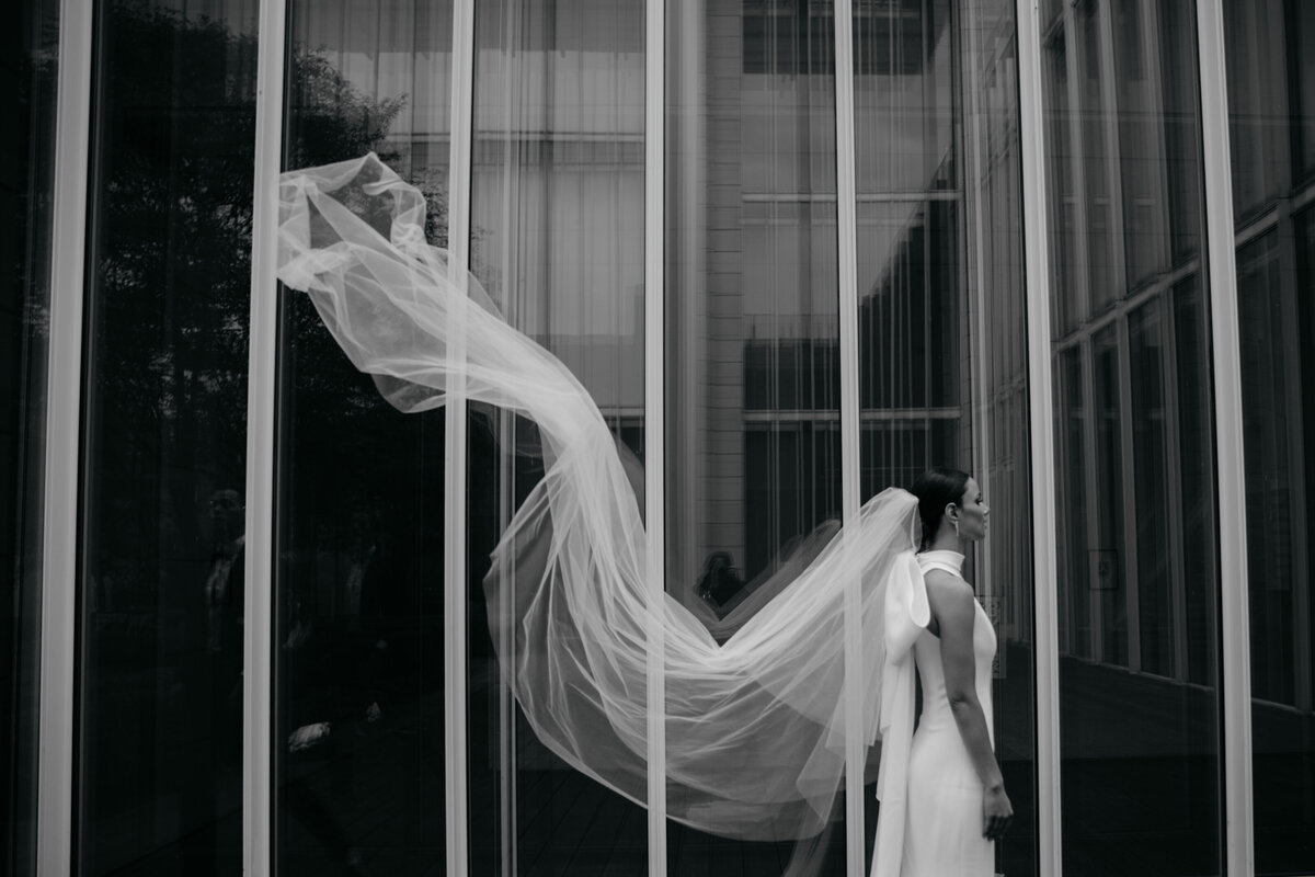 Bride's long veil blows in the wind during portraits at the Chicago Art Museum