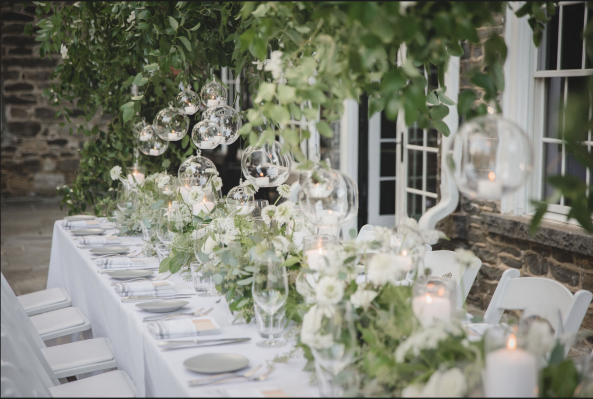 Elegant garden-style tablescape with lush white floral installation at Hasbrouck House, a top Hudson Valley event venue.

