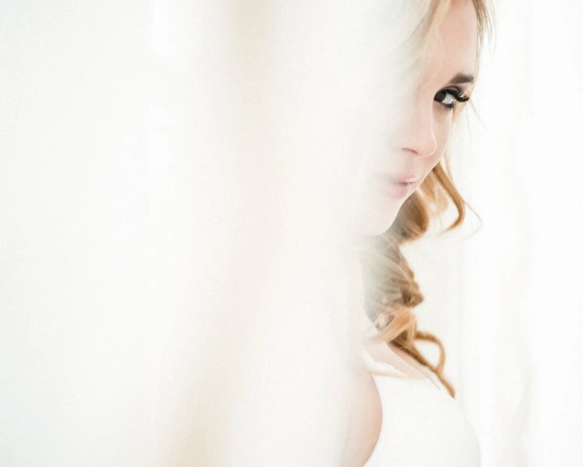 A woman peeking around a veil.