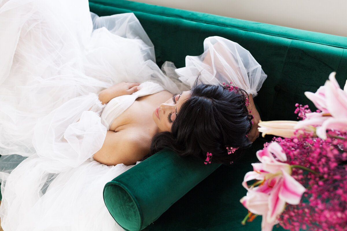 bride lying on emerald green sofa