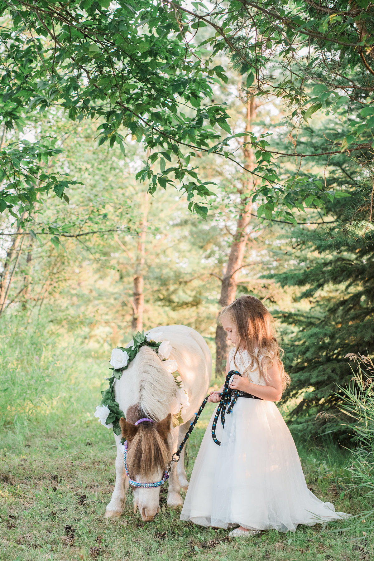 photo of little girl and pony in a forest