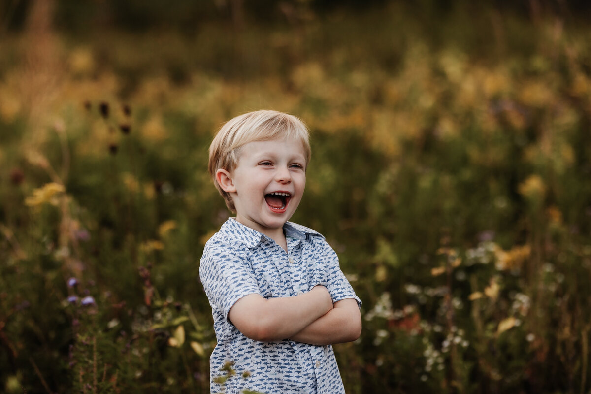 A boy laughs in the flowers.