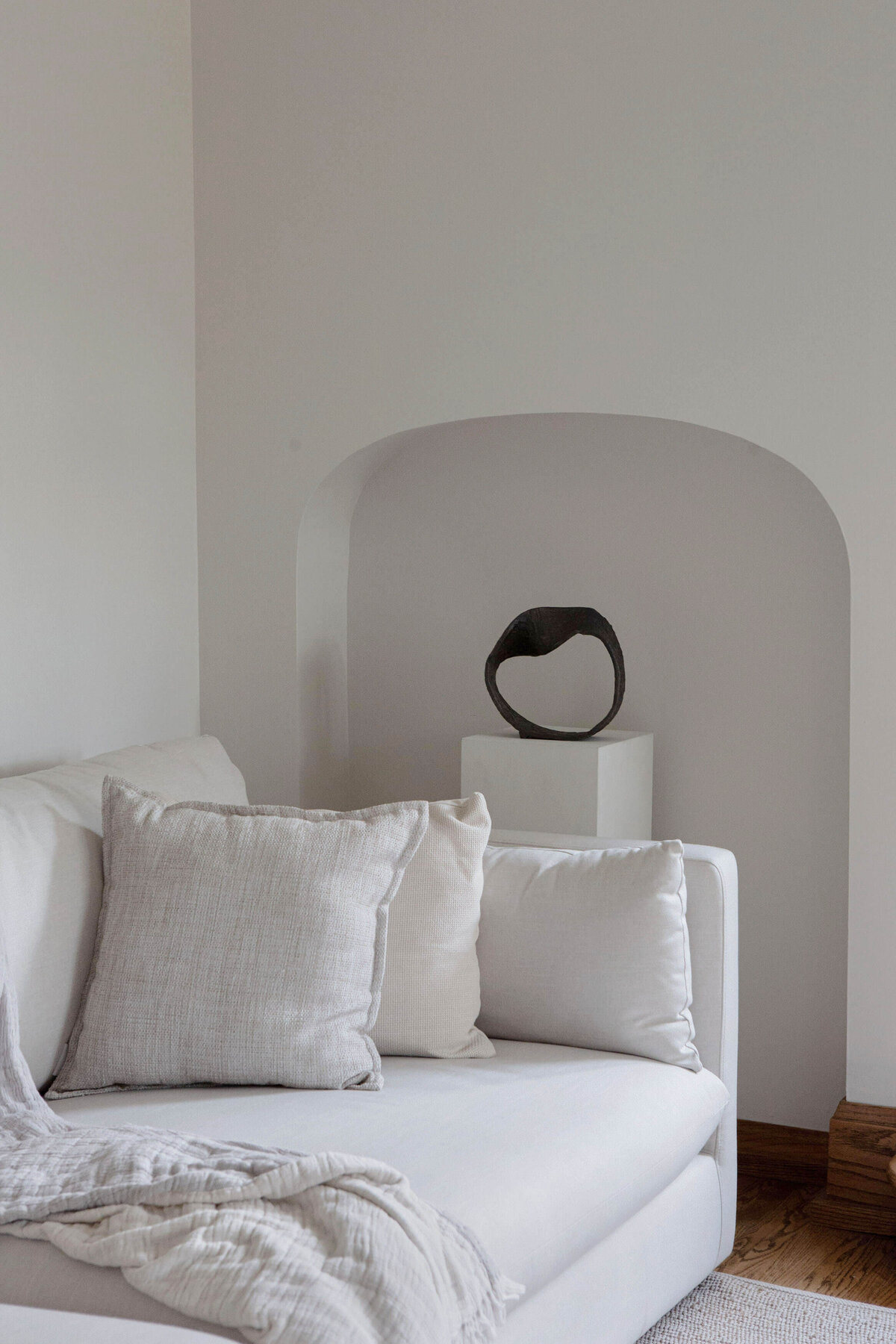 details of white sofa  pedestal with modern sculpture in character home living room