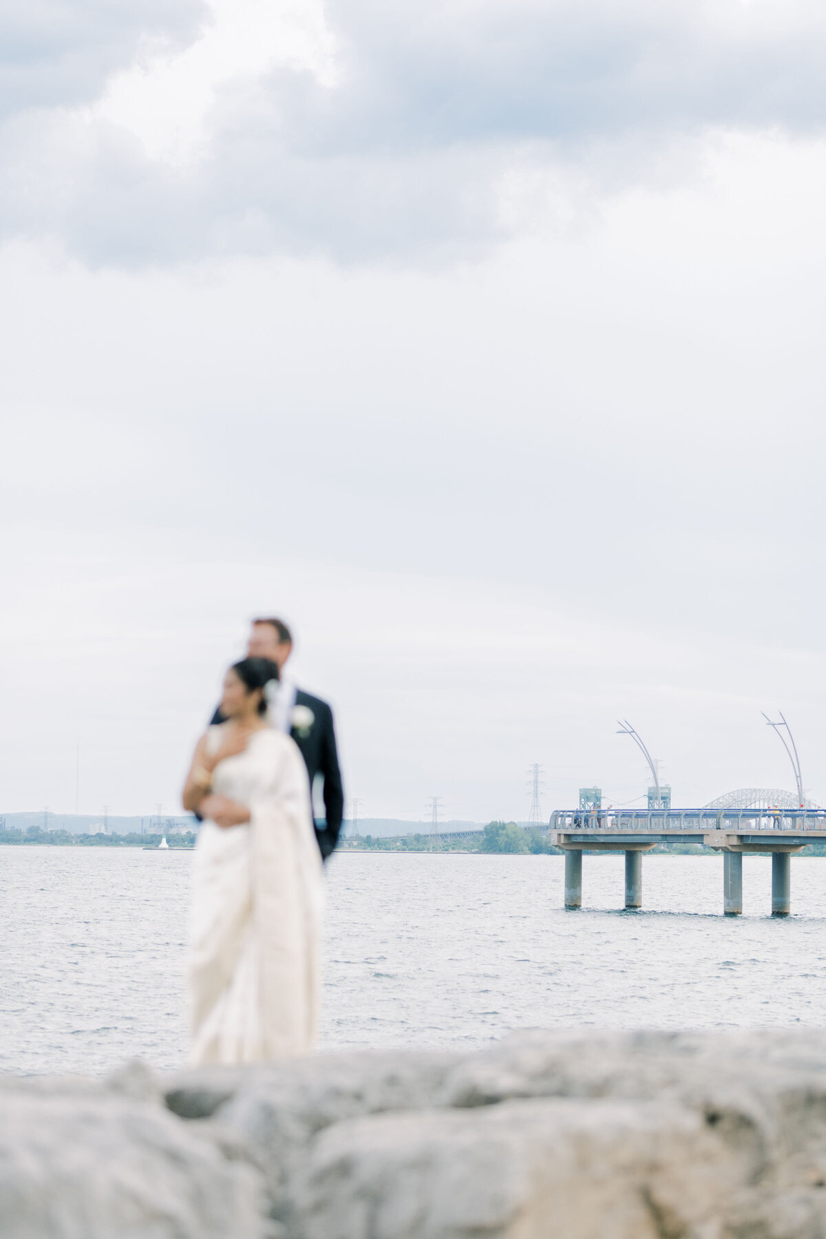 bride and groom  holding each other  over the lake Ontario in burlington