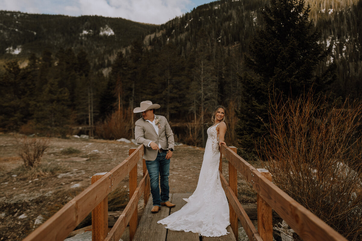 couple stand on colorado bridge posing for photographer