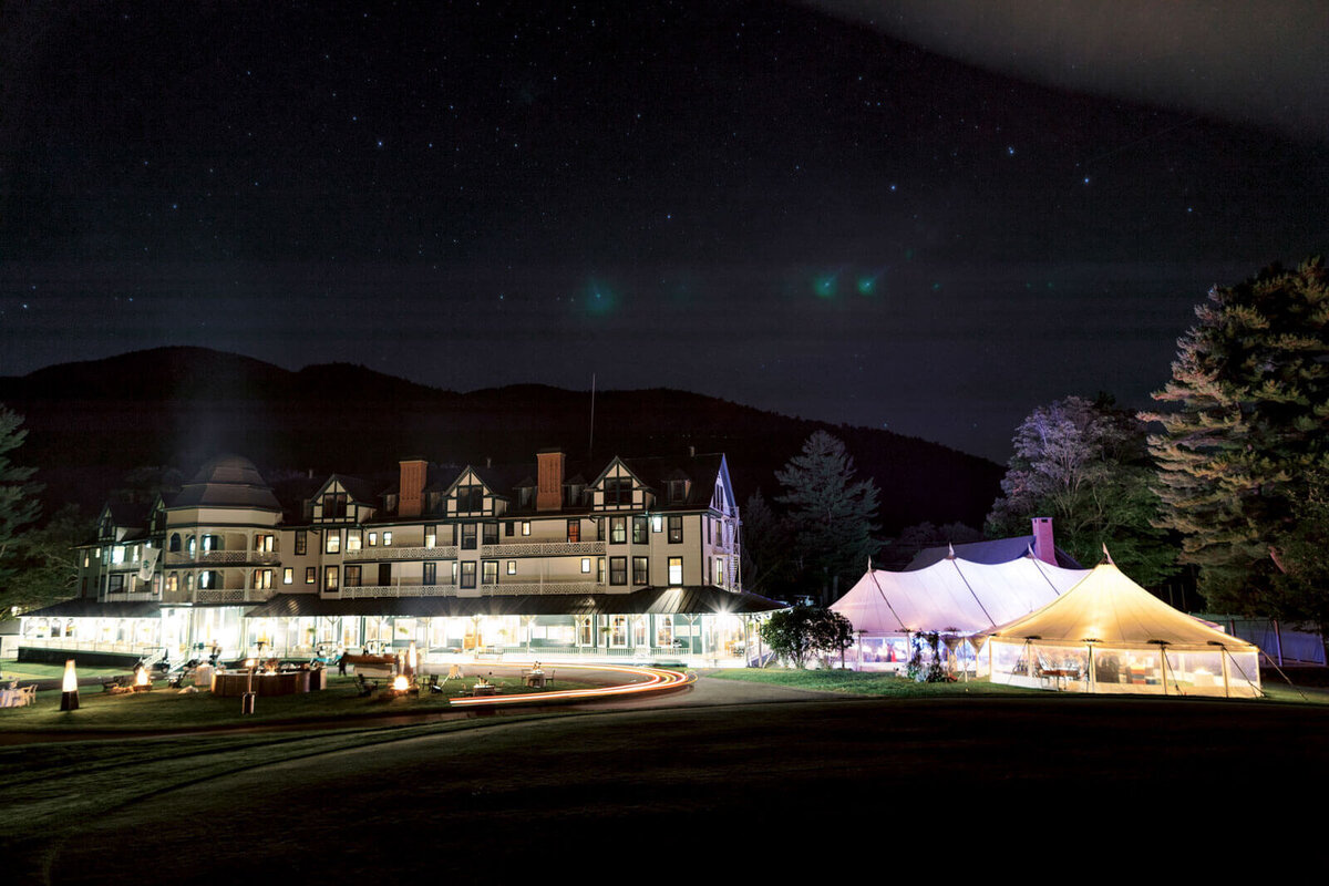 A night view of the elegant tent wedding venue and beautiful hotel from afar, at The Ausable Club, NY. Image by Jenny Fu Studio