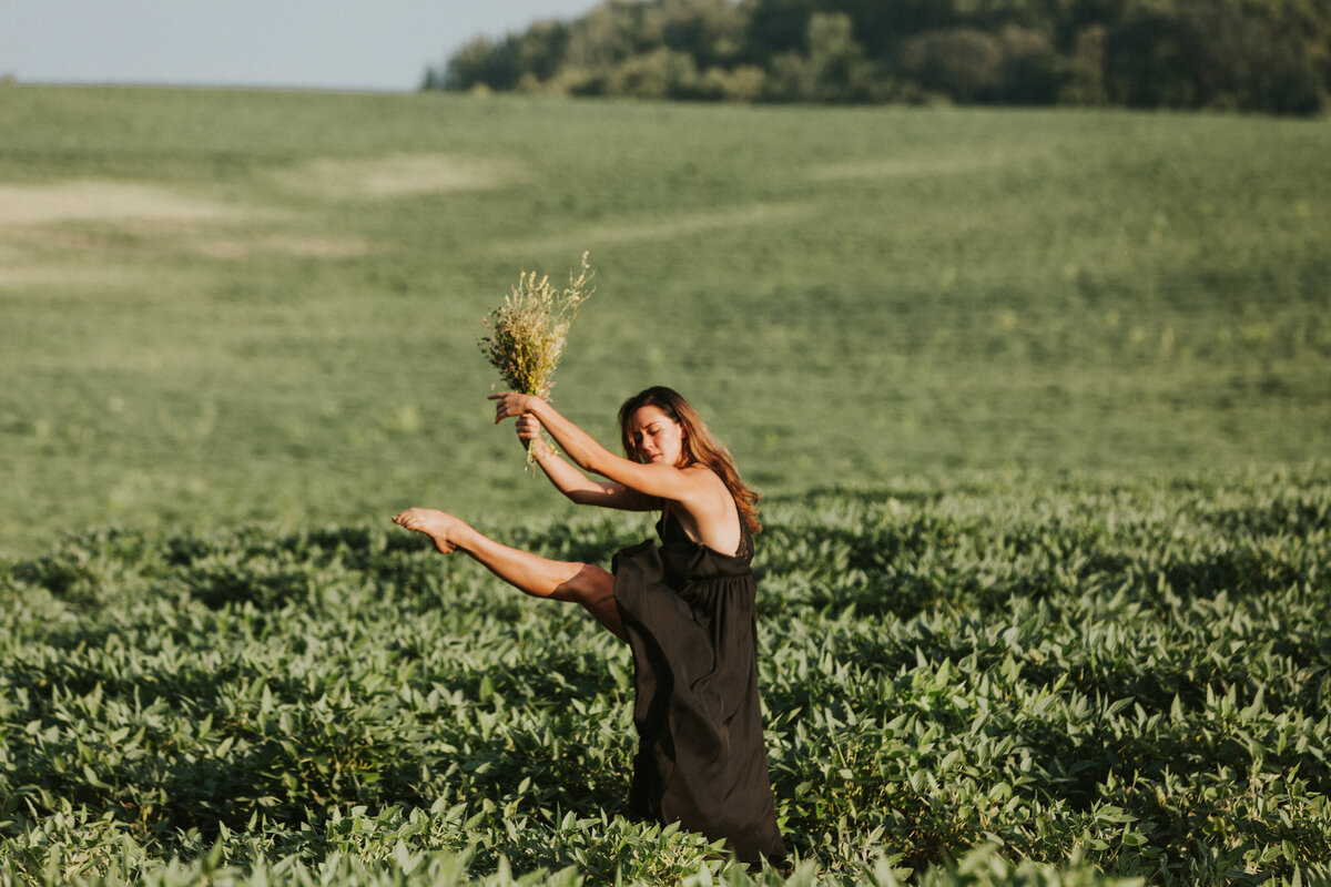 Woman dances with flowers in open field