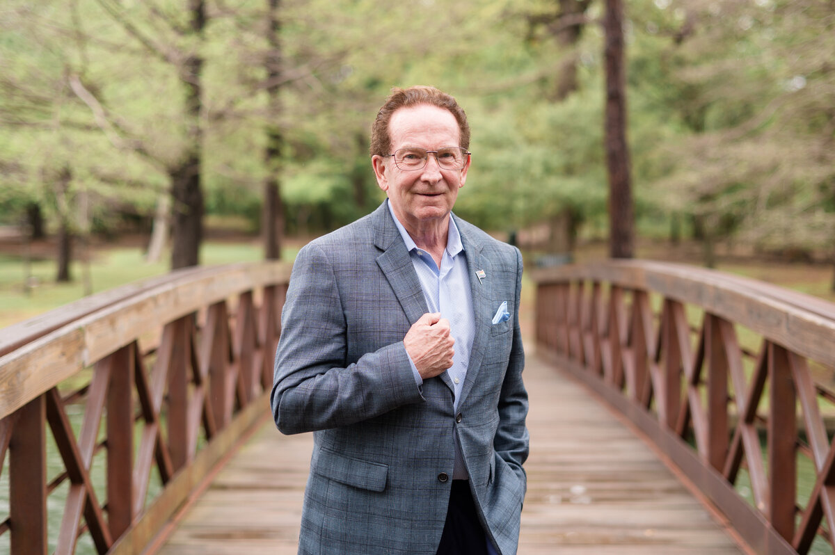 Lissette G captures branding headshot of suited man on a Houston park bridge