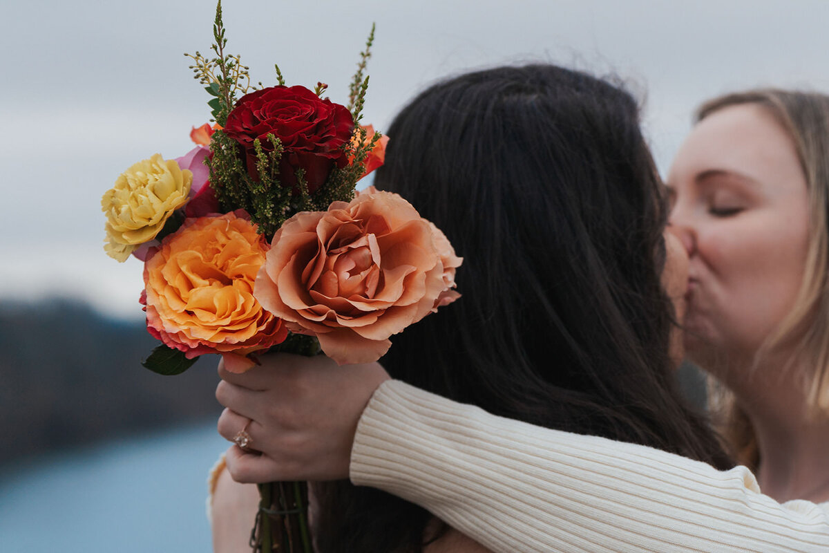Women kiss holding their bouquet