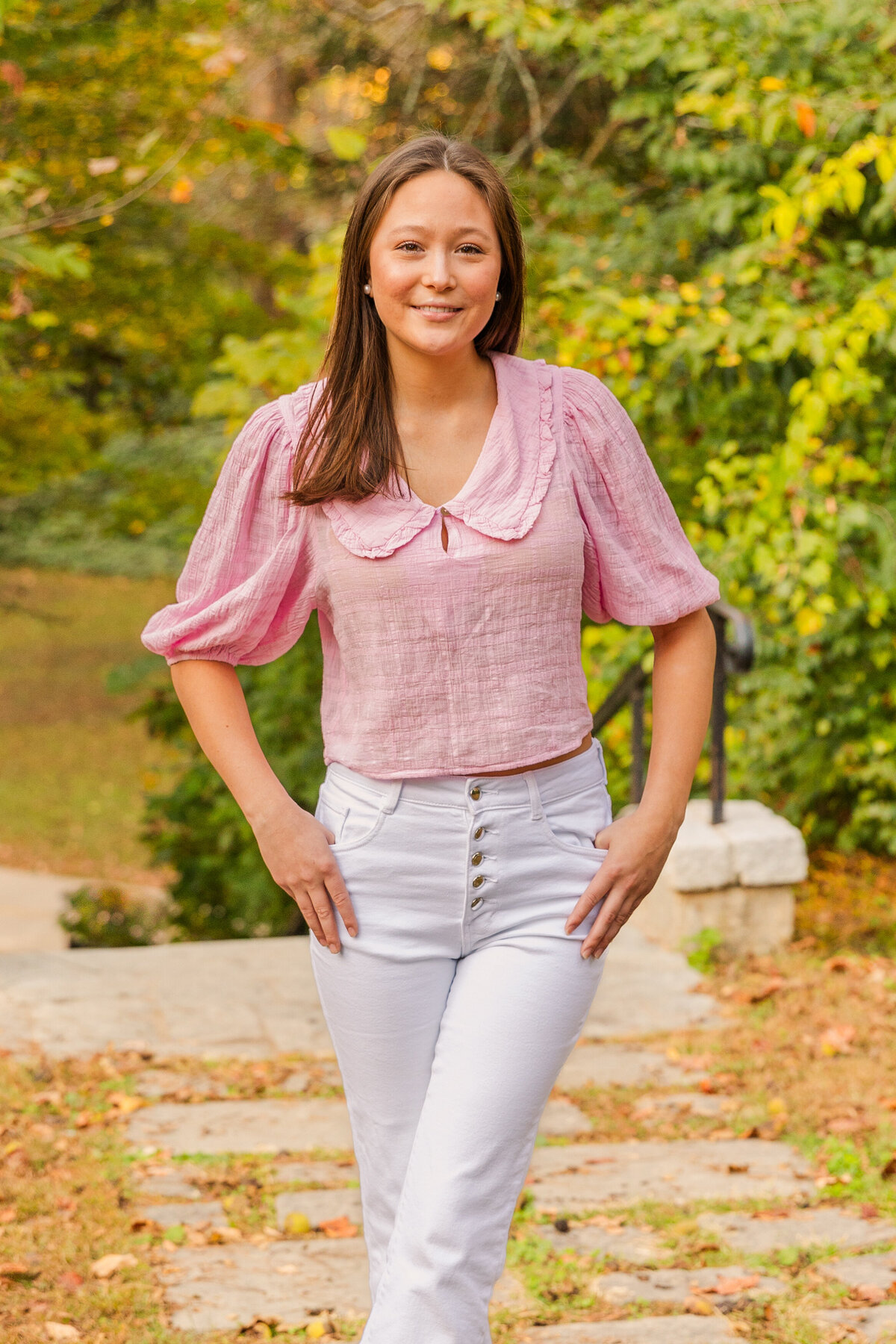 teenager wearing a white jeans and a pink blouse looking at the camera hands in front pockets during lifestyle photoshoot