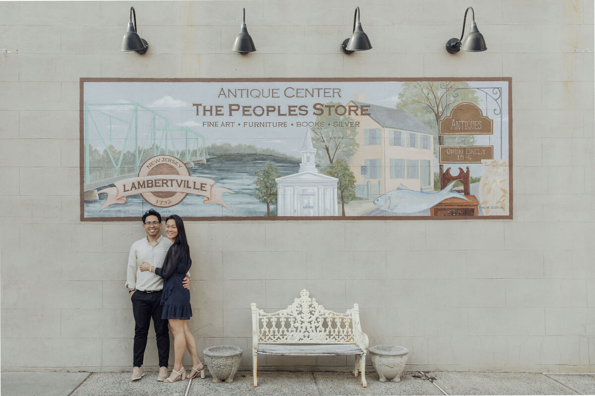 Asian couple on bridge near mural during summer engagement session in Lambertville Hunterdon County New Jersey