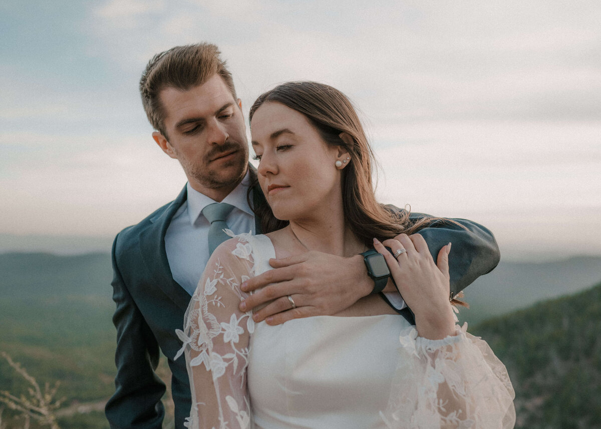 groom embracing bride over shoulder and looking at each other during elopement on mogollon rim in payson, arizona