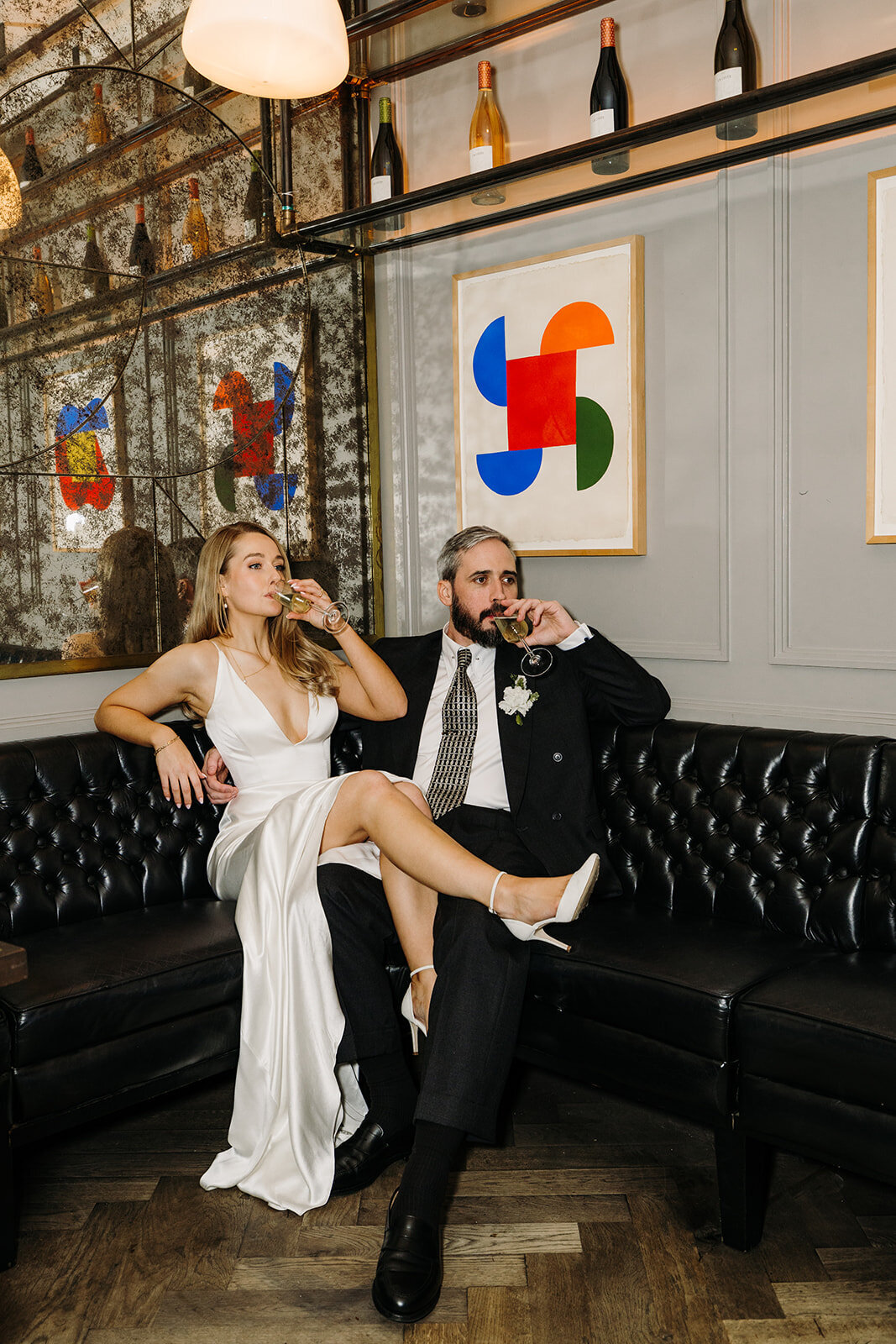 Bride and groom sitting on a black leather couch & drinking at Roberta’s in Dublin, Ireland