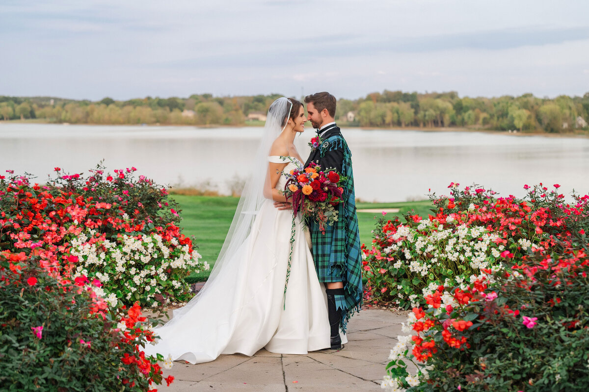 youngstown wedding photographer takes picture of a married couple in the rose garden at The Lake Club Ohio with Lake Evans behind them